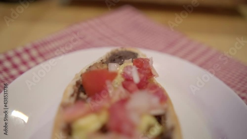 Traditional Mexican mollete on a plate above white and red checkered napkin photo