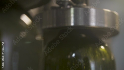 Slow motion, close-up pour wine into a bottle, on the conveyor belt. Wine bottle filling along a conveyor belt in a wine bottling factory. Automated wine bottling production line.