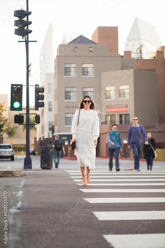 Adult happy woman crossing the street in the city.