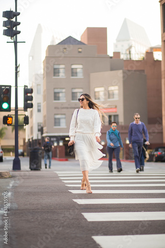 Adult happy woman crossing the street in the city.