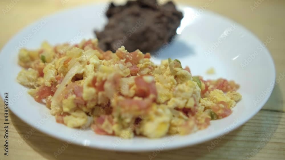 Mexican-style eggs and refried beans on a white plate Mexican-style eggs and refried beans on a white plate