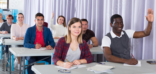 Multinational group of adult students listening teacher in classroom