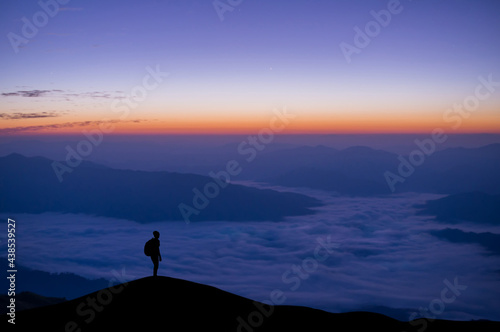 Silhouette of young traveler and backpacker watched the star and milky way and foggy landscape at the morning alone on top of the mountain.