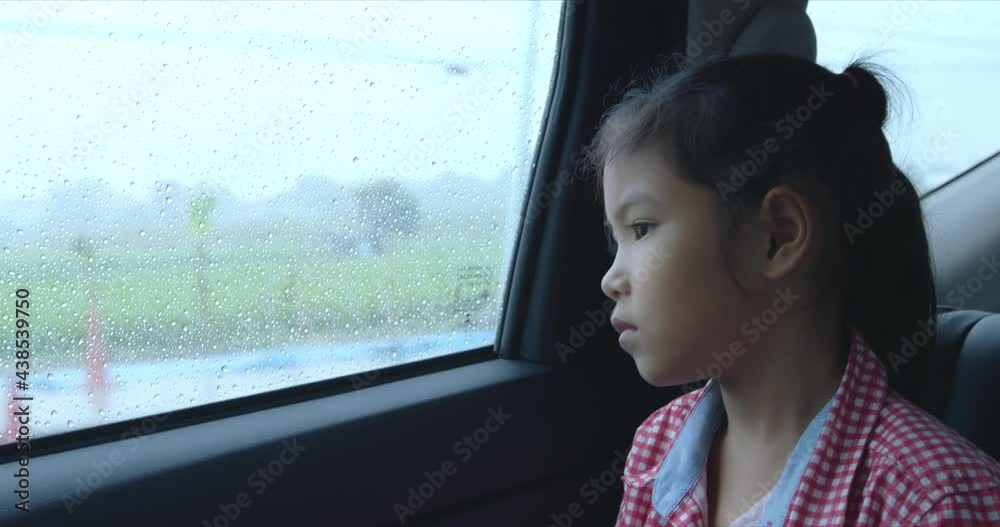 Asian child girl is looking out from car window in the rainy day Asian child girl is looking out from car window in the rainy day