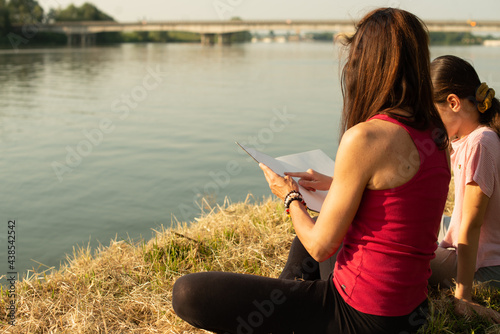 Mother and daughter reading and spending an afternoon at the park in summer photo