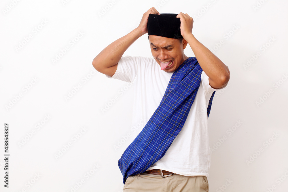 Stressed asian man using a cap and scabbard while holding his head. Ramadan concept. Isolated on white background Stressed asian man using a cap and scabbard while holding his head. Ramadan concept. Isolated on white background