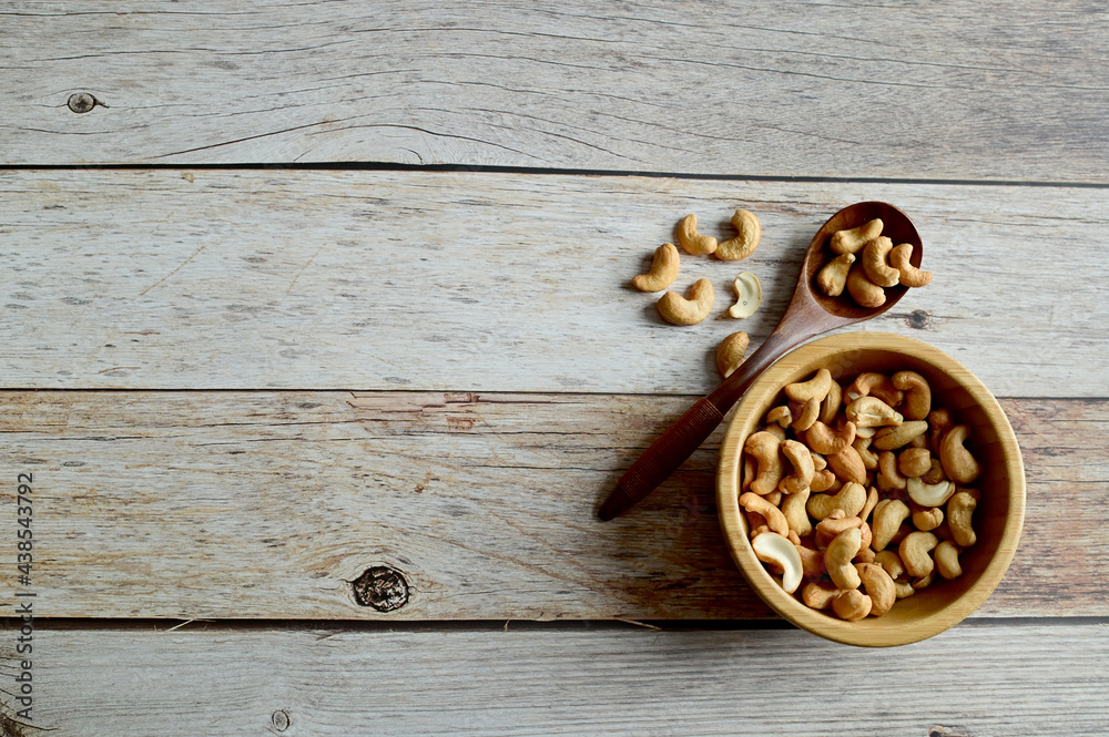 Top Views of Cashew Nuts in a wooden bowl and wooden spoon isolated on the wooden background, Full depth of field. Top Views of Cashew Nuts in a wooden bowl and wooden spoon isolated on the wooden background, Full depth of field.