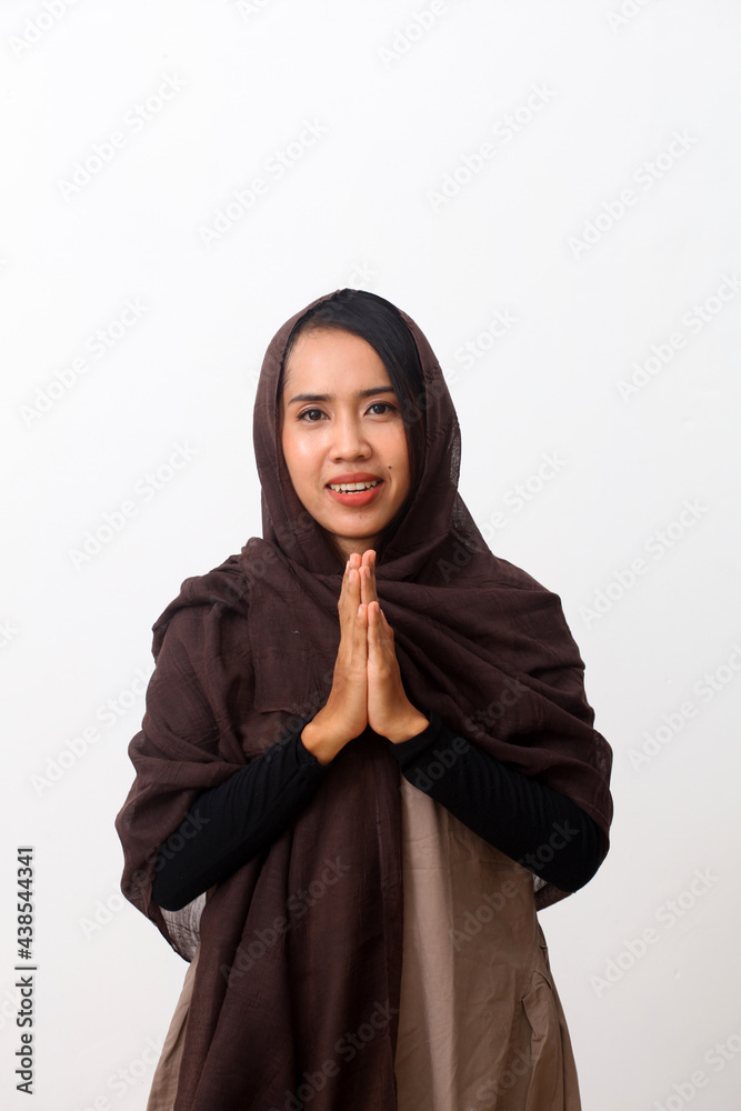 Portrait of asian woman in Muslim dress stands up in a greetting pose to Namaste hands, welcoming guests, Eid Fitr greeting. Isolated on white background Portrait of asian woman in Muslim dress stands up in a greetting pose to Namaste hands, welcoming guests, Eid Fitr greeting. Isolated on white background