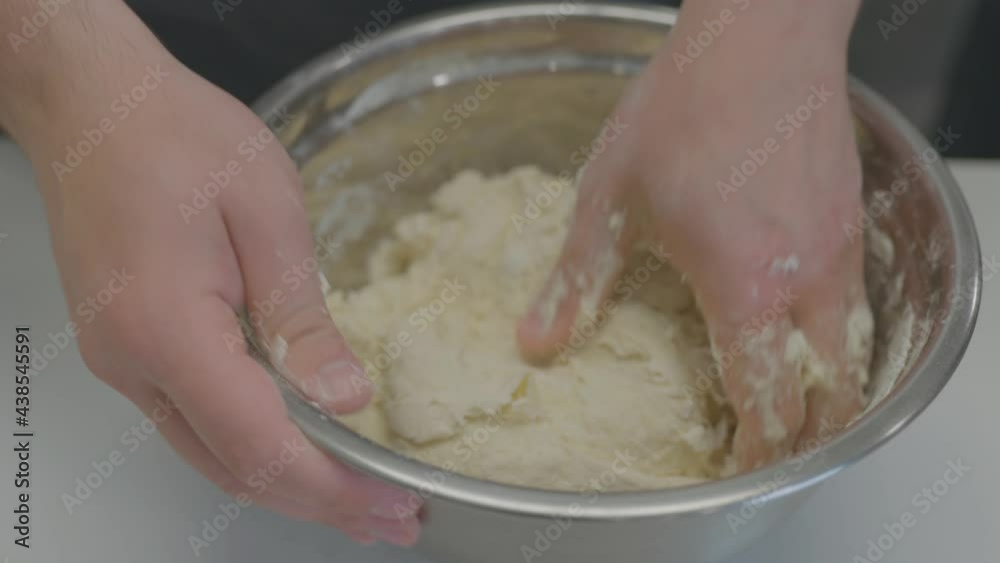 Close-up of a baker's hands skillfully kneading dough in a large metal bowl. Close-up of a baker's hands skillfully kneading dough in a large metal bowl.