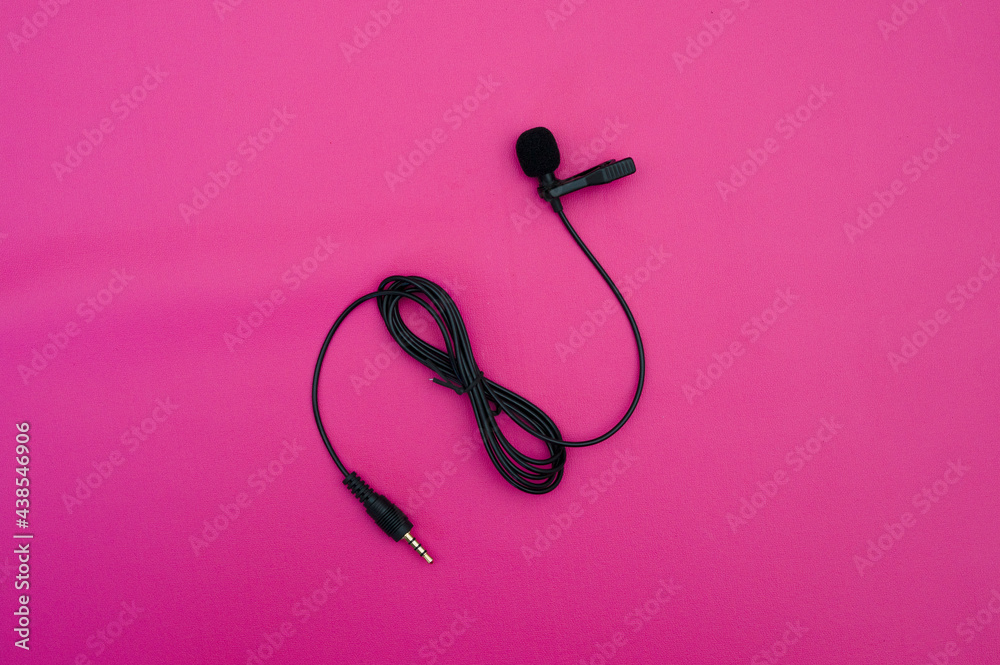 Fototapeta premium clip on mic on pink background. clip on microphone with wire captured on pink. minimal object shot.