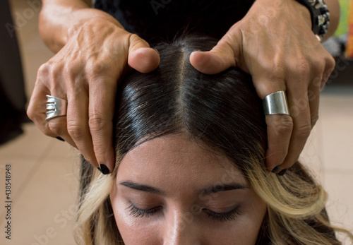 Hairdresser pulling hair from her client's forehead with her hands