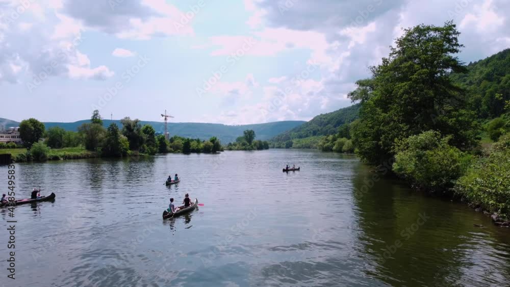 People on a boat with oars float on the river near the forest and field People on a boat with oars float on the river near the forest and field