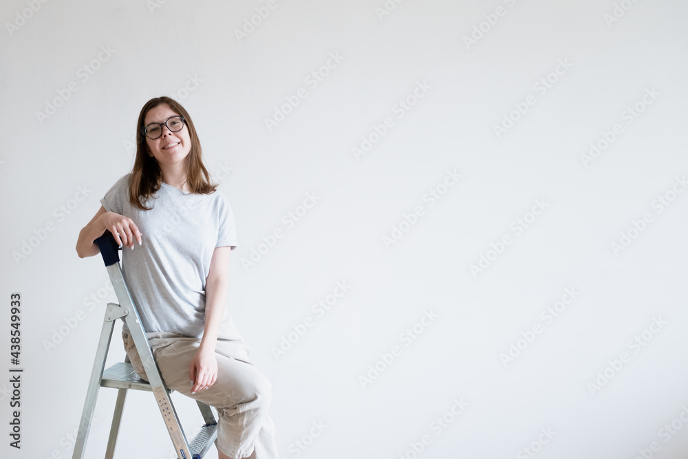 Joyful smiling girl on a stepladder. Repair ladder. Joyful smiling girl on a stepladder. Repair ladder.