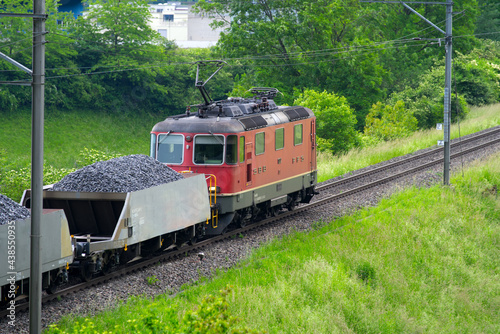 Cargo train near village Eglisau, canton Zurich, loaded with crushed rock. Photo taken June 9th, 2021, Eglisau, Switzerland.