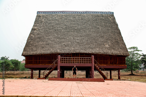 A tourist exploring a traditional architecture of a Bahnar ethnic stilt house or Rong House in Pleiku countryside, Vietnam photo