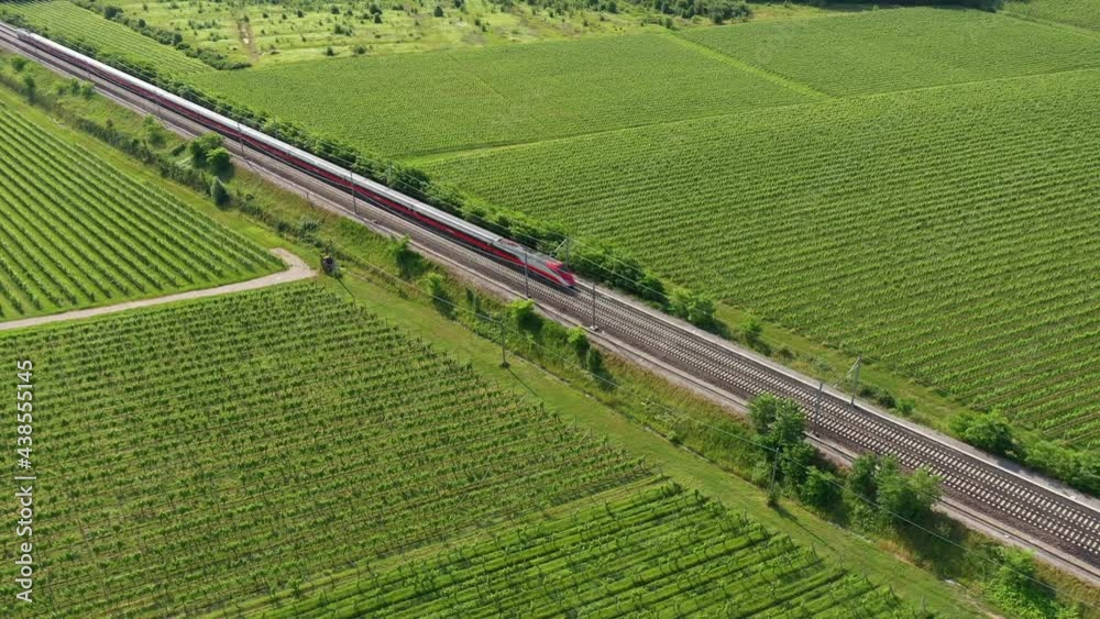 Traffic red train aerial view. The movement of a red train at high speed between the vineyards, top view.