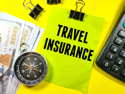 Business concept.Text TRAVEL INSURANCE on sticky note on notebook with calculator,banknote,compass and paper clips on yellow background.