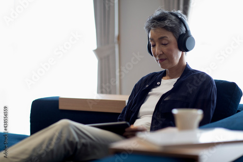 ヘッドホンをつけてタブレットPCを見る日本人シニア女性 photo