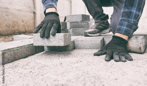 Worker lining paving slabs path