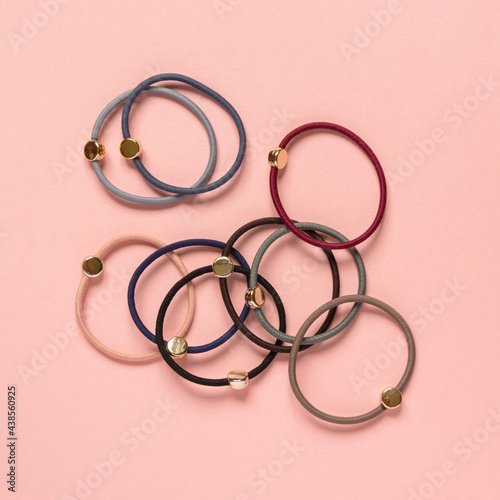 Set of multicolored hair ties on pink background, top view