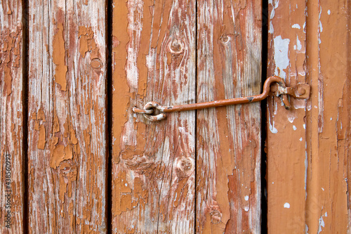 Old rusty hinges on brown wooden cracked door close up