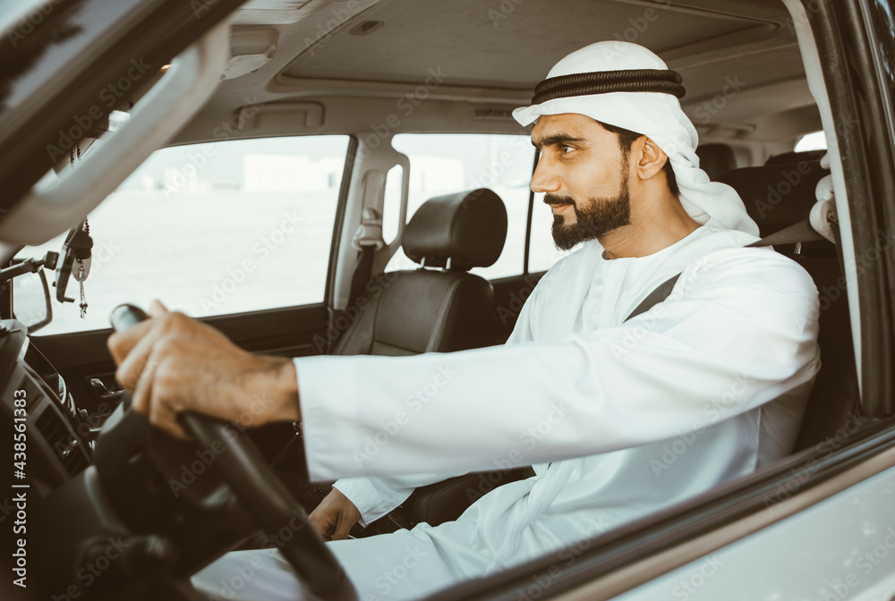 Handsome man with uae traditional outfit driving in Dubai. Middle eastern man with kandura in the car Handsome man with uae traditional outfit driving in Dubai. Middle eastern man with kandura in the car