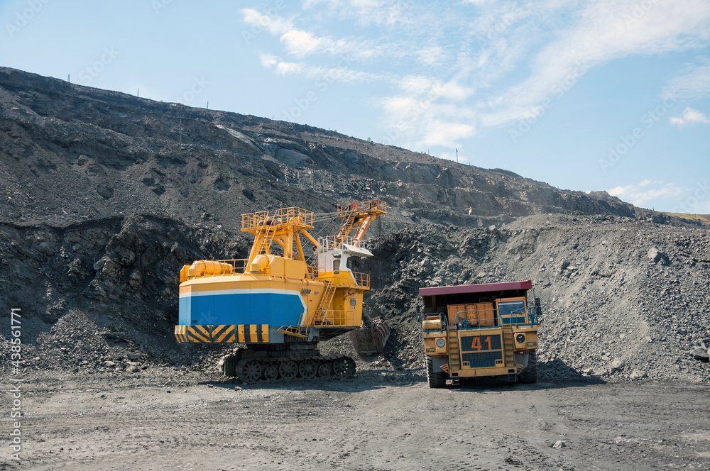 Quarry excavator loading iron ore into the heavy dump truck in iron ore open cast mine