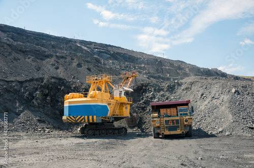 Quarry excavator loading iron ore into the heavy dump truck in iron ore open cast mine © sashagrunge