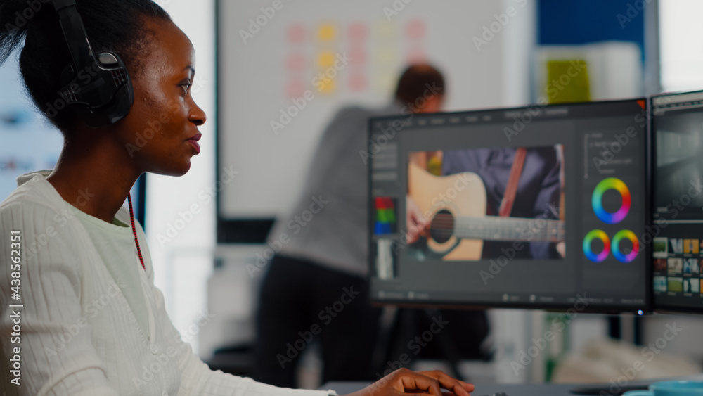 African video editor with headset listening music wihile editing