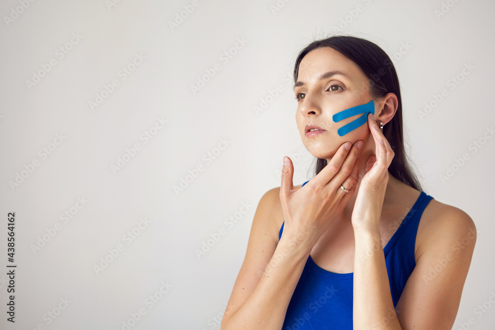 portrait of a young woman with pasted konesiotape for rejuvenation and face tightening