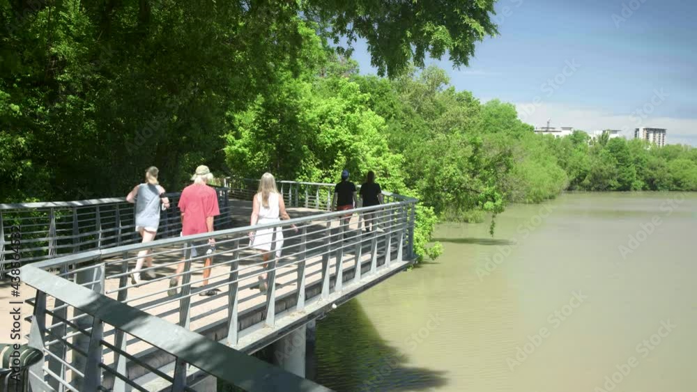 Jogging woman and two walking couples enjoy a sunny day on the lakeside boardwalk in Austin, Texas. Jogging woman and two walking couples enjoy a sunny day on the lakeside boardwalk in Austin, Texas.