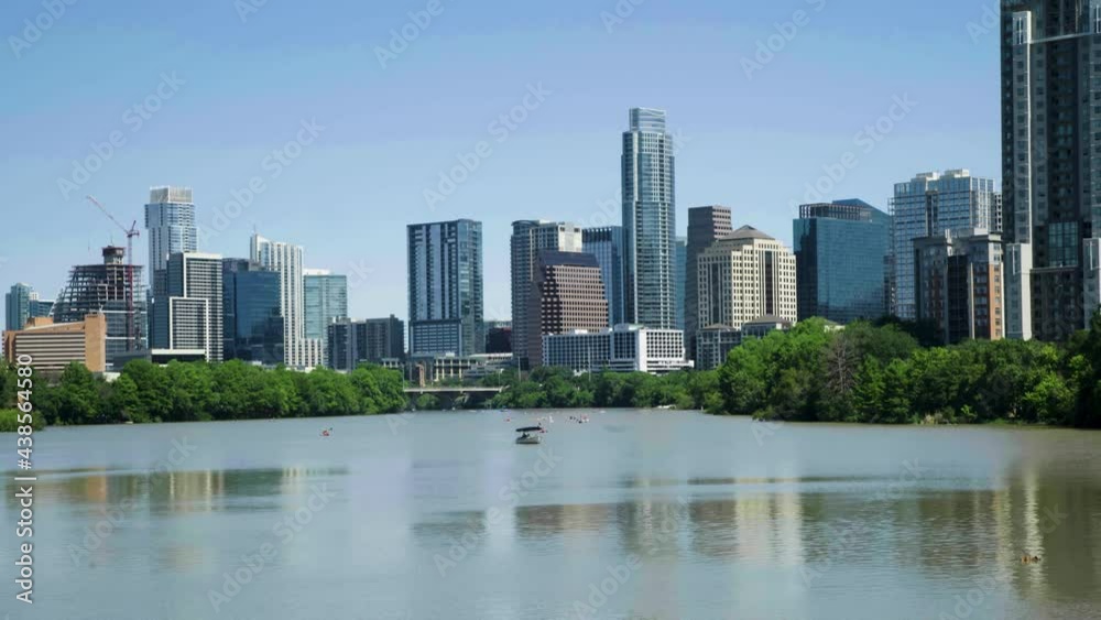 Austin, Texas skyline over Town (Ladybird) Lake on a sunny day with boats, kayaks, and paddle boarders enjoying the sunny day. Buildings reflect in the placid water. Austin, Texas skyline over Town (Ladybird) Lake on a sunny day with boats, kayaks, and paddle boarders enjoying the sunny day. Buildings reflect in the placid water.