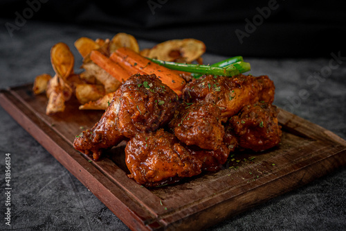 Tasty barbecued wings with french fries and vegetables