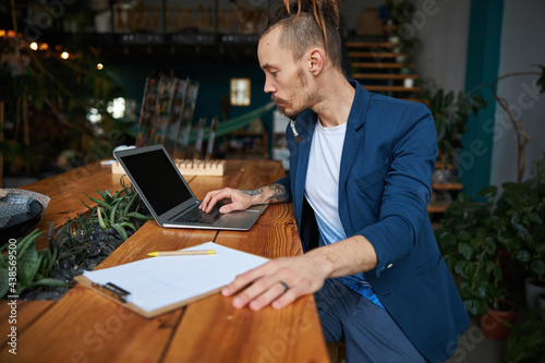 Stylish young man using modern laptop at work