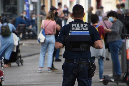A policeman seen from behind watches people in the street