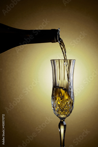 Sparkling wine is poured from a bottle into a glass.