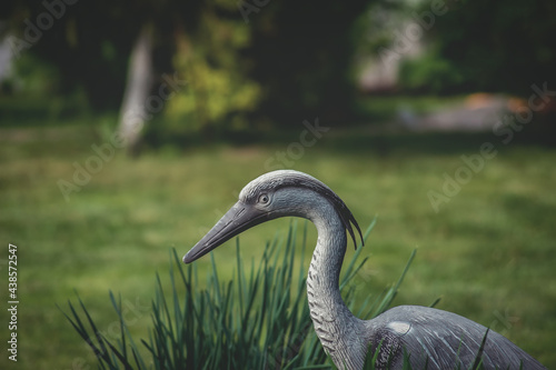 Bird statue in the garden. Artificial figure of a bird on a green background.
