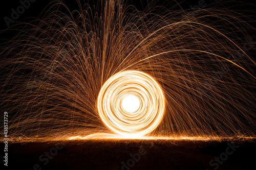 Spinning and burning Steel wool sparkle fire in the circle shape with long speed shutter shoot glowing light line to the ground.