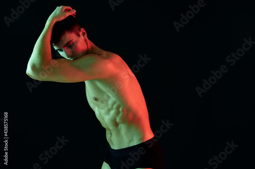 guy athlete in black shorts gesturing with his hands on a dark background © SHOTPRIME STUDIO