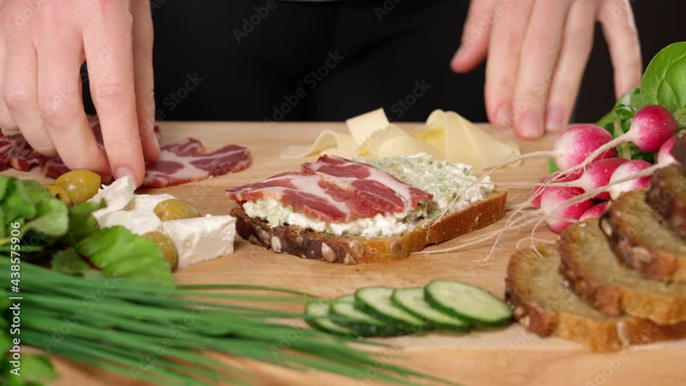 Woman's hands making sandwich with feta cheese and ham on wooden board, close-up Woman's hands making sandwich with feta cheese and ham on wooden board, close-up