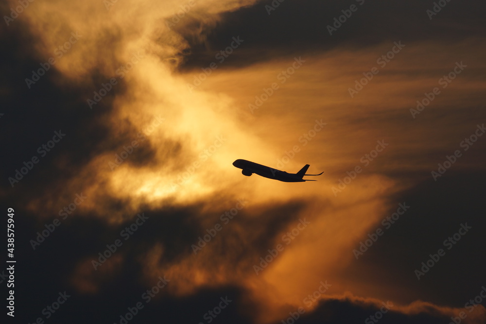 Early morning sky with silhouette of plane taking off