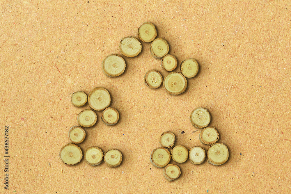 Recycling symbol made of wood slices on recycled paper background - Concept of ecology Recycling symbol made of wood slices on recycled paper background - Concept of ecology