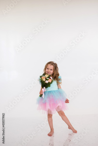a little blonde girl in a festive dress holds a bouquet of fresh flowers on a white background. Happy birthday girl