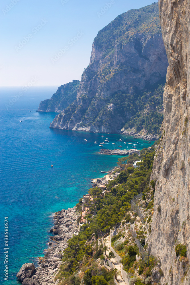 View of the coastline of the island of Capri, Italy, with one of its seaside rock formations known as the Faraglioni, vertical photo