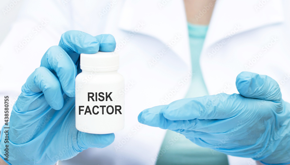 Risk Factor inscription on a can of medicine in the hands of a doctor in blue styres, close-up Risk Factor inscription on a can of medicine in the hands of a doctor in blue styres, close-up