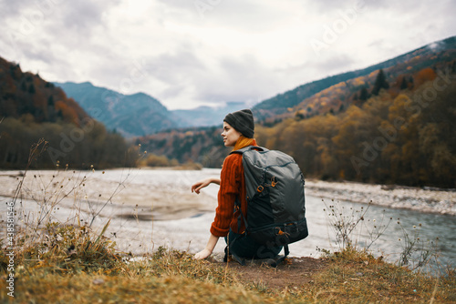 woman hiker on the banks of the river in autumn and mountains in the distance clouds weather nature