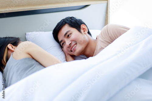 Happy Young Asian couple resting in bed