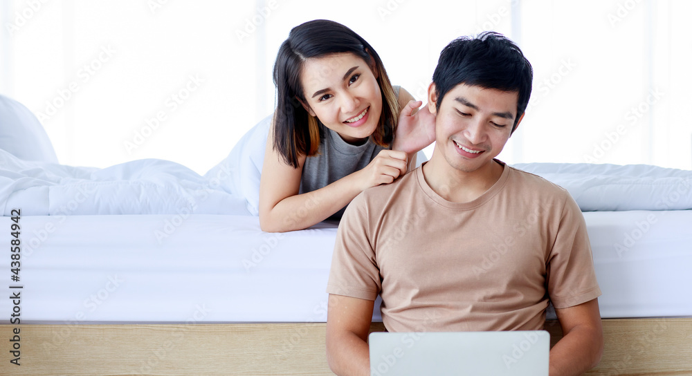 Loving couple with laptop resting in bedroom Loving couple with laptop resting in bedroom