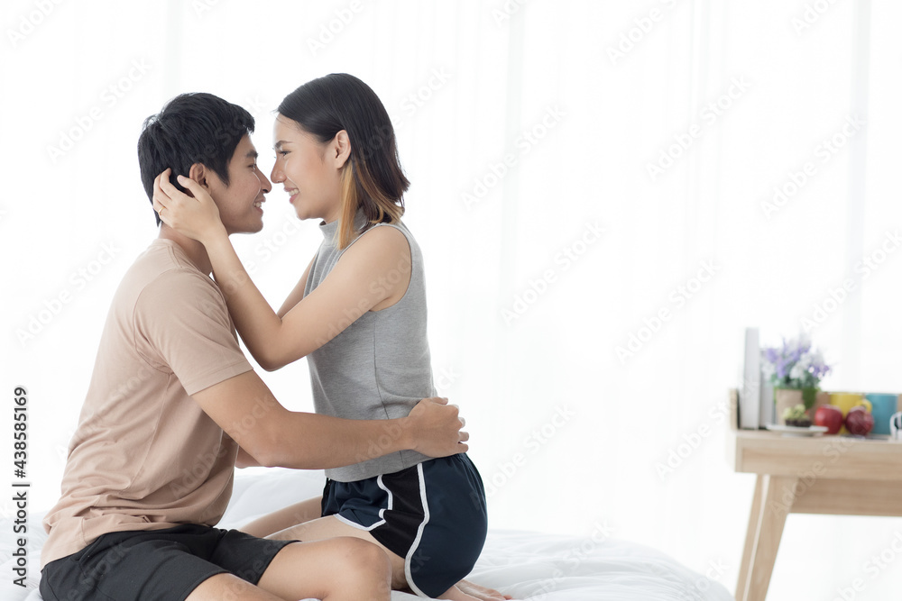 Delighted Asian couple hugging on bed Delighted Asian couple hugging on bed