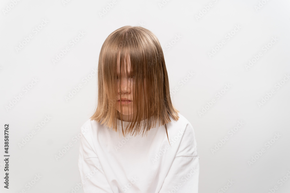 sad little girl with hair covers the face on a white background. sad little girl with hair covers the face on a white background.